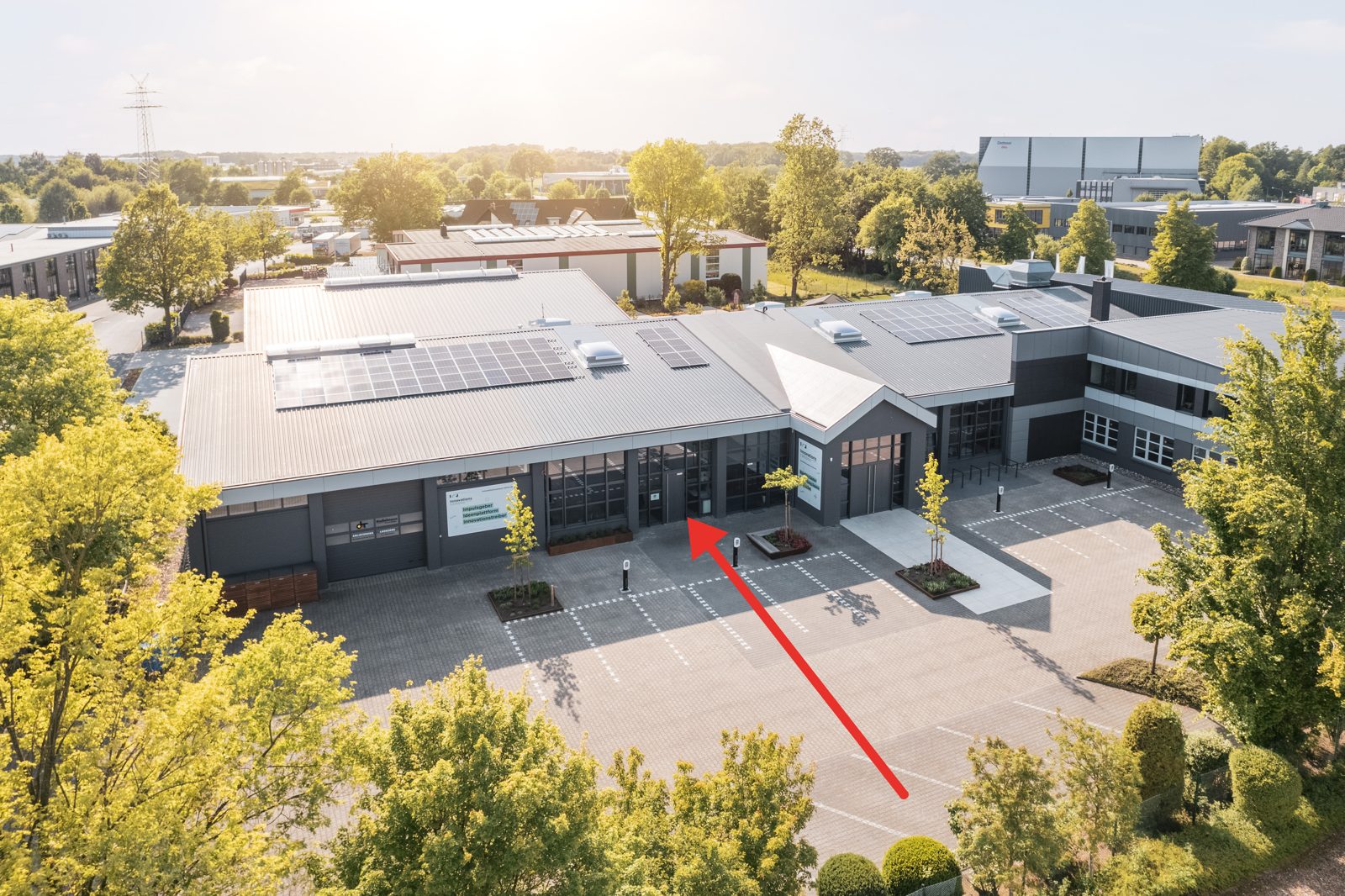 Luftaufnahme des InnovationsCampus Lohne, Industriering 4. Ein roter Pfeil zeigt auf die Eingangstür von Timo Lutz, Team für Industriefotografie, links neben dem Haupteingang.