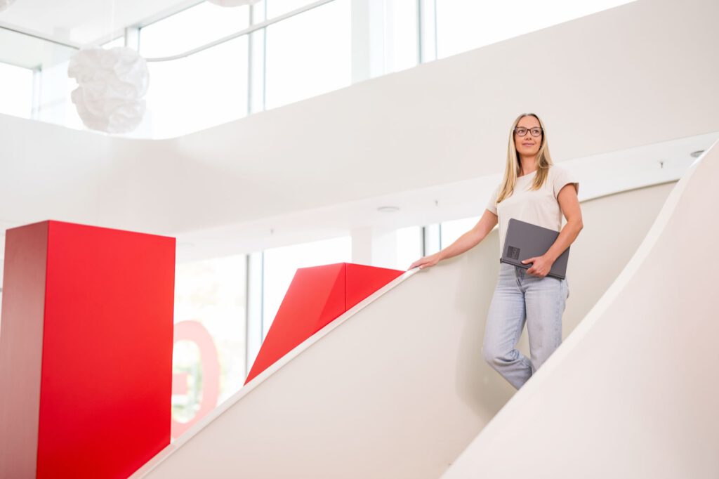 Mitarbeiterin mit Tablet an der geschwungenen Treppe im Neubau von STULZ