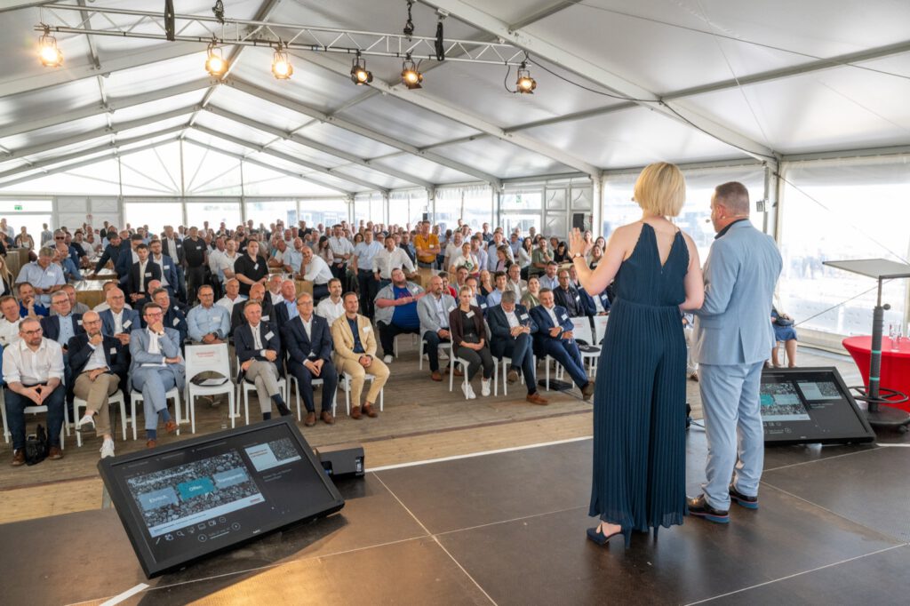 Volles Festzelt bei der Eröffnung des STRABAG-Standorts im Neusser Hafen, vorn die Moderation auf der Bühne