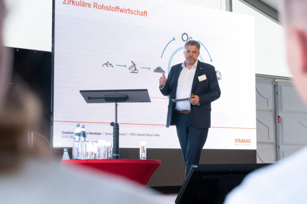 Georg Lehde stellt im Zelt den neuen Standort vor, dahinter eine Folie zur zirkulären Rohstoffwirtschaft