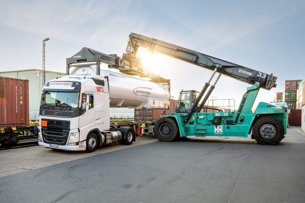 Containerstapler hebt einen Tankcontainer neben einem Lkw, Gegenlicht am Roland-Terminal Bremen