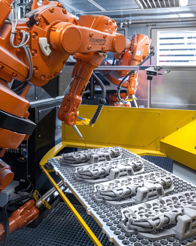 Roboter über einem Gitterträger mit gedruckten Sandkernen