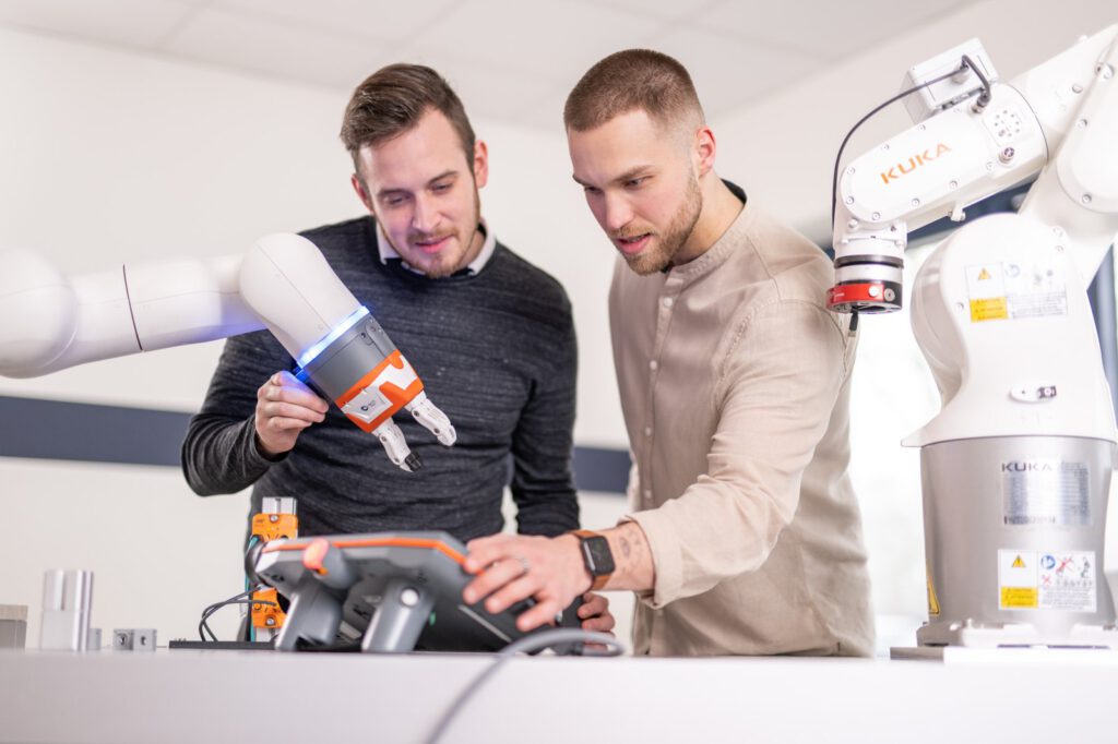 Industriefotografie für Lenkering in Steinfeld: zwei Mitarbeiter am Cobot