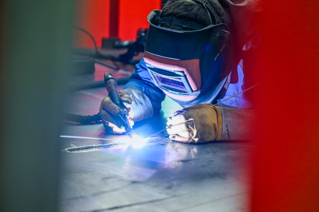 Schweißer mit Schutzhelm bei der Arbeit, Funken und blaues Licht