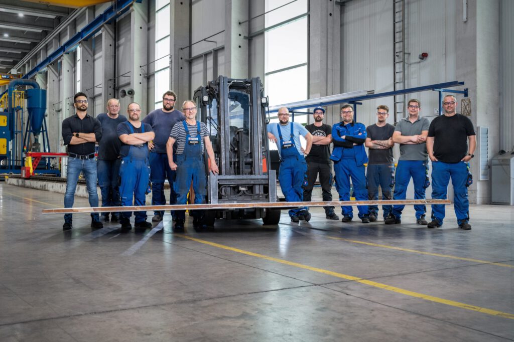 Gruppenbild der Mitarbeitenden von NobelClad in der Produktionshalle in Liebenscheid