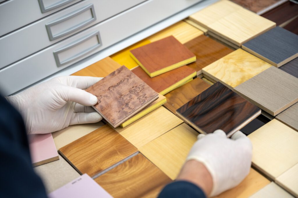 Hände in weißen Handschuhen legen Furniermuster in verschiedenen Hölzern aus