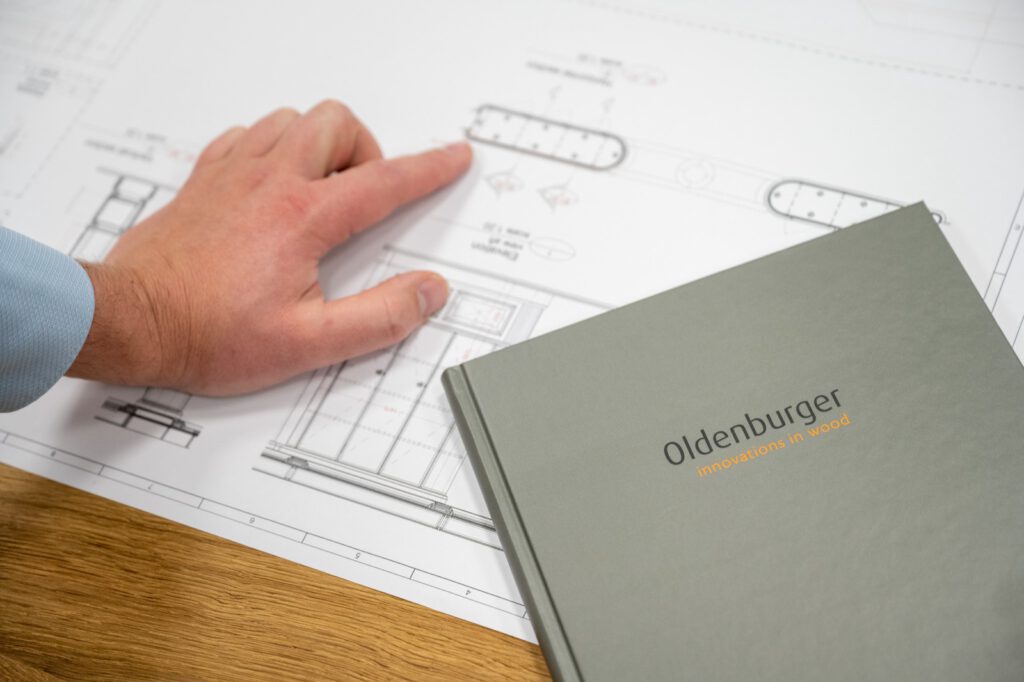 Hand zeigt auf eine technische Zeichnung, daneben eine Mappe mit dem Oldenburger-Logo