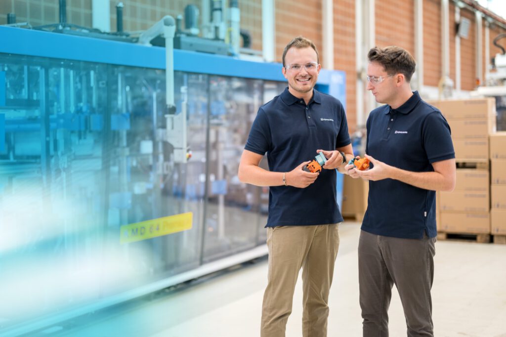 Zwei Mitarbeiter von KAPSTO betrachten in der Produktion gemeinsam Schutzkappen