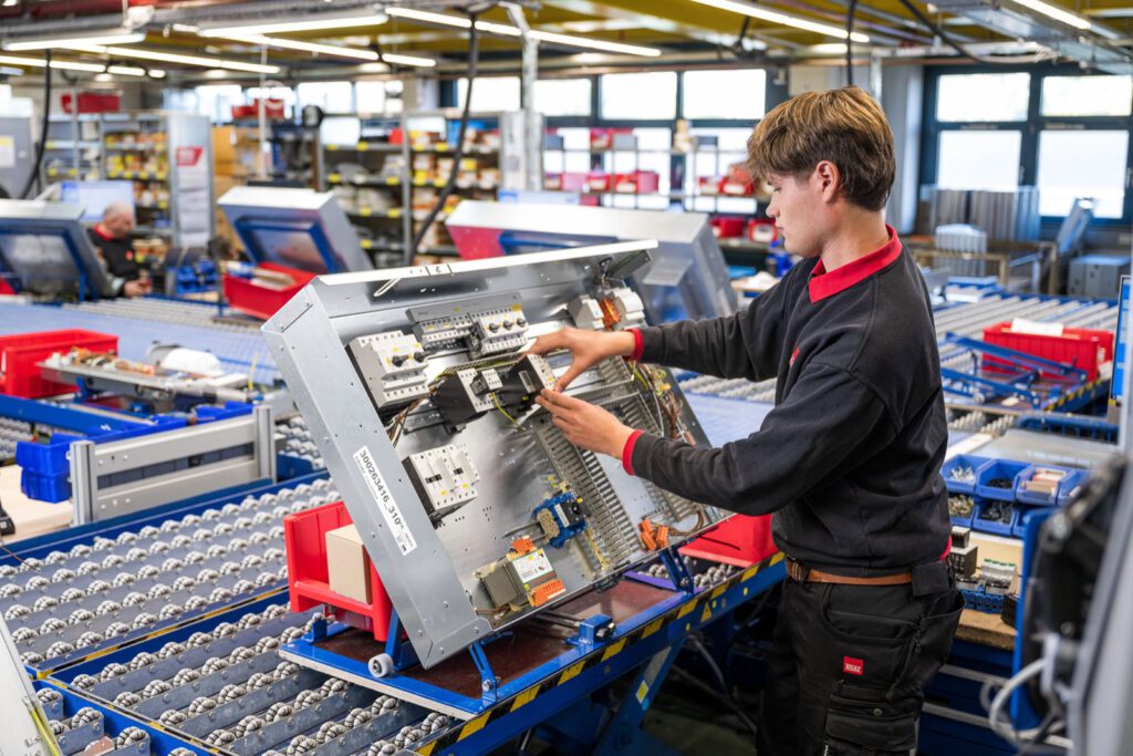 Mitarbeiter montiert Elektronik an einem Klimagerät in der E-Fertigung von STULZ