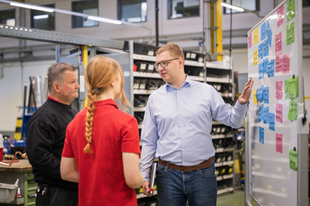 Drei Mitarbeitende von STULZ besprechen sich vor einem Planungsboard mit Haftnotizen