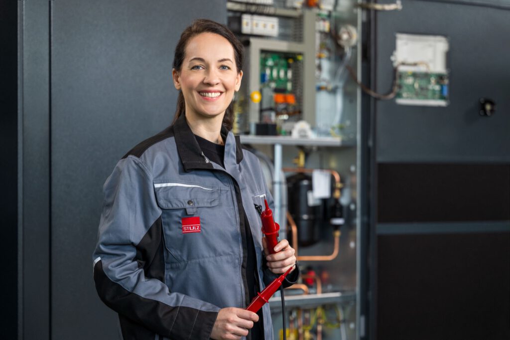 Servicekraft in Arbeitskleidung vor einem geöffneten Schaltschrank bei STULZ