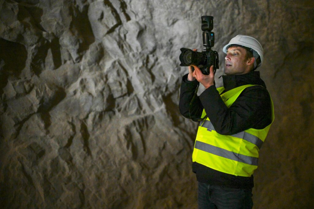 Fotograf mit Helm und Warnweste fotografiert im Stollen der Grube