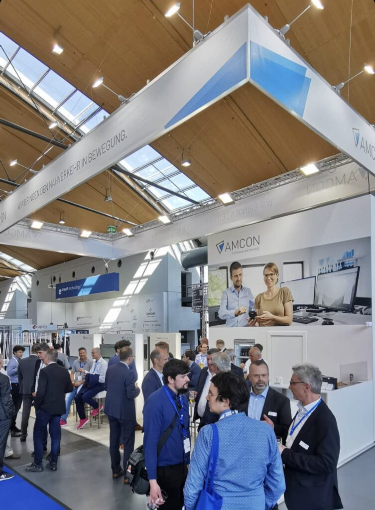 Messestand von AMCON mit unserem Bild zweier Mitarbeitender als großer Messewand