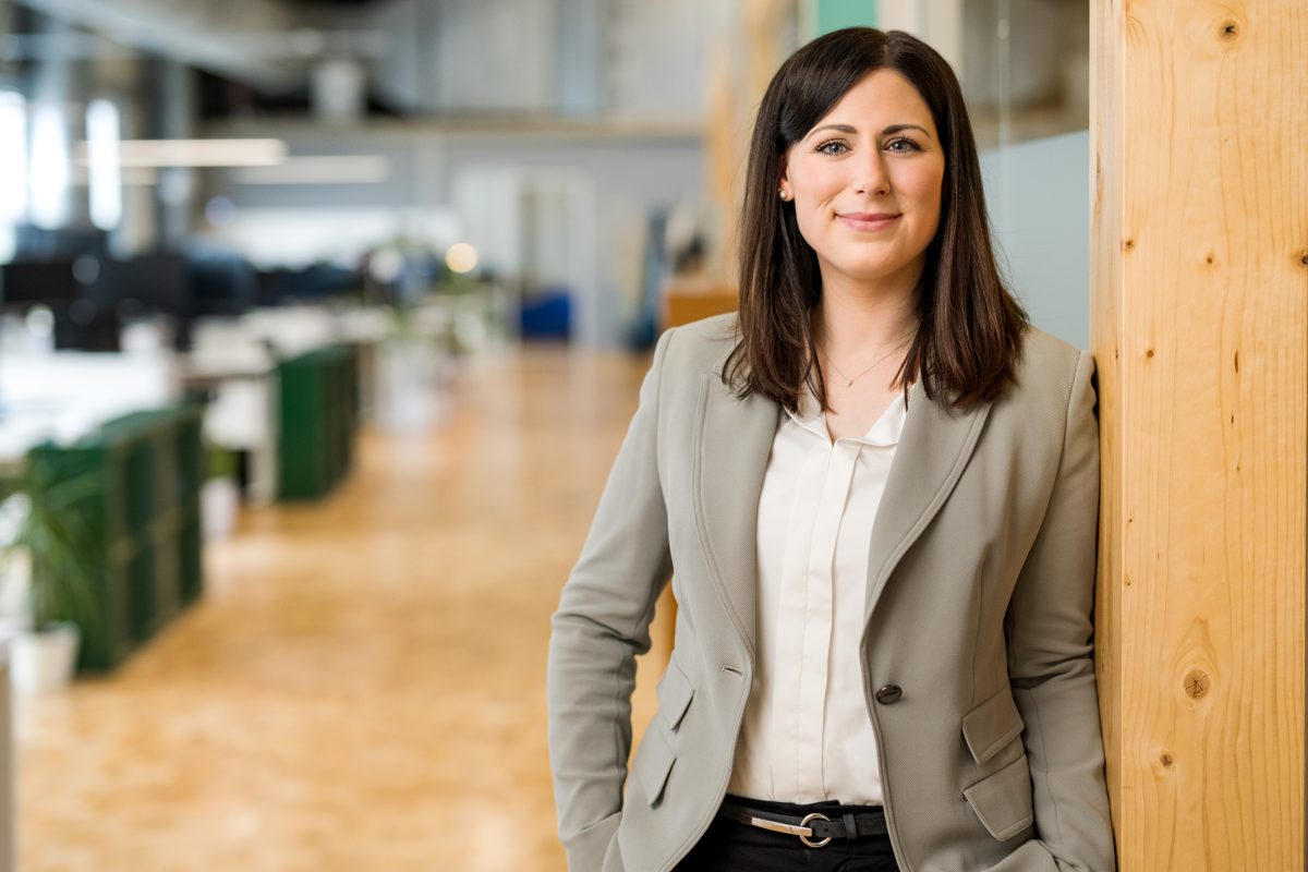 Frau in hellem Blazer und heller Bluse in einem offenen Büro