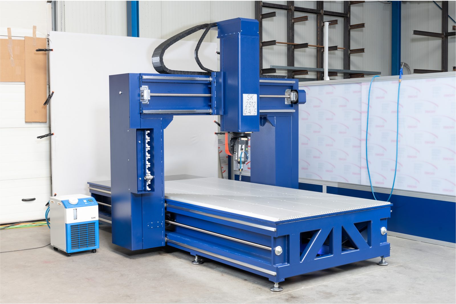 Vorher: CNC-Portalfräsmaschine in der Halle, mit Regalen und Kabeln im Hintergrund