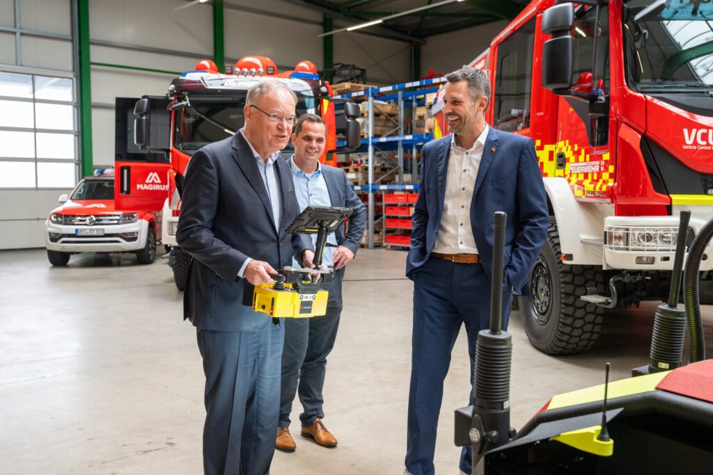 Stephan Weil hält in der Fahrzeughalle von Alpha Robotics eine Fernsteuerung
