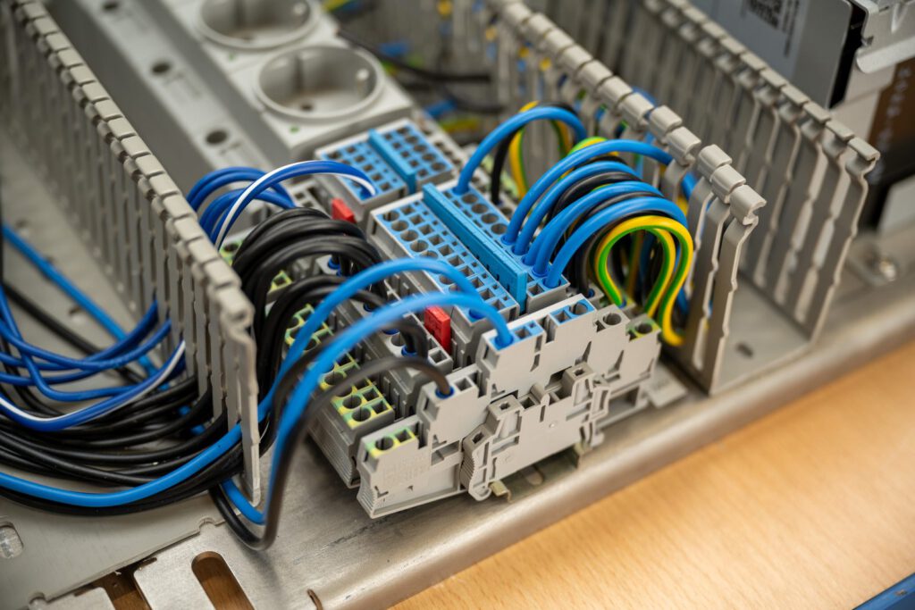 Blaue, schwarze und gelbgrüne Kabel in einem Schaltschrank
