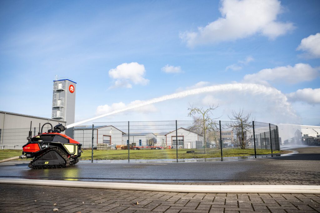 Der Wolf R1 von Alpha Robotics mit einem Wasserbogen vor dem Firmengebäude in Vechta