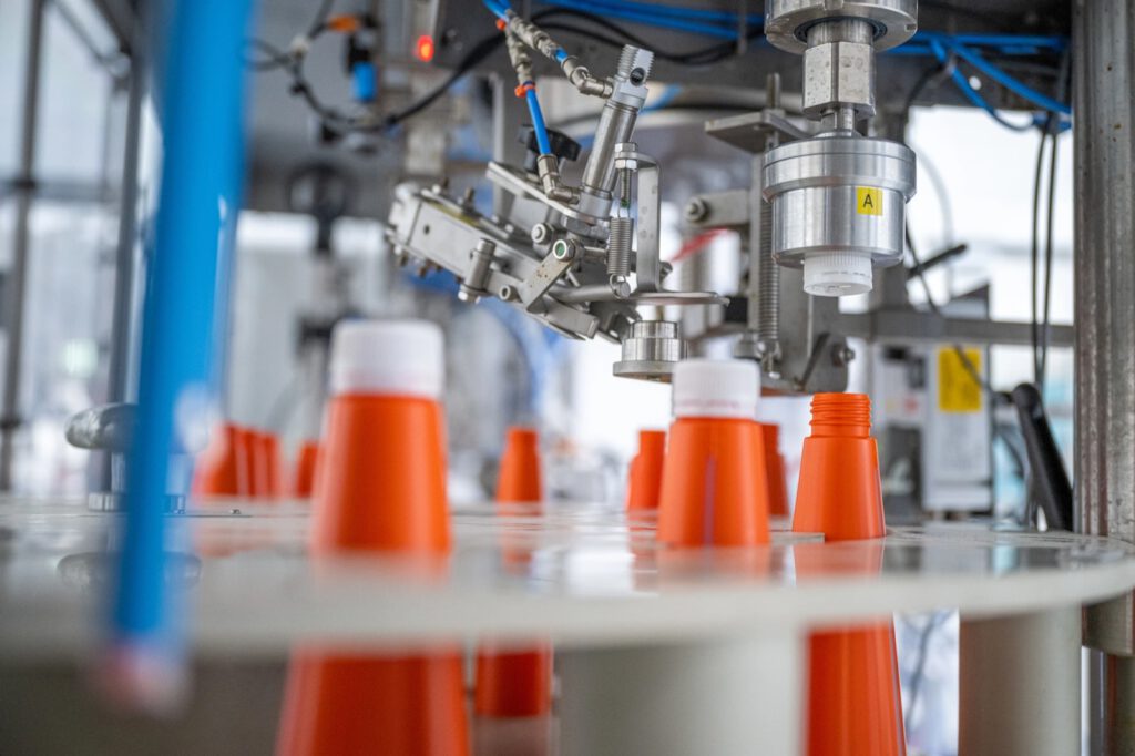 Orange Flaschen auf dem Drehteller einer Abfüllanlage bei Biochem, aus der Nähe